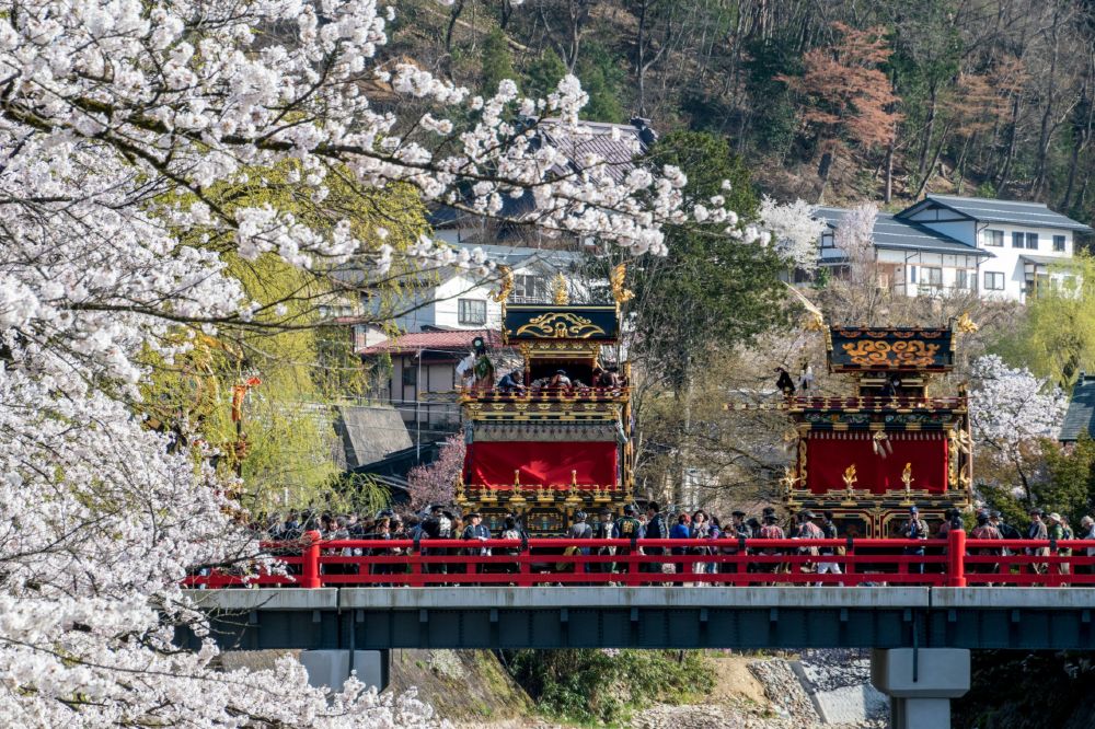 Festival floats cross a
        bridge in Takayama.
